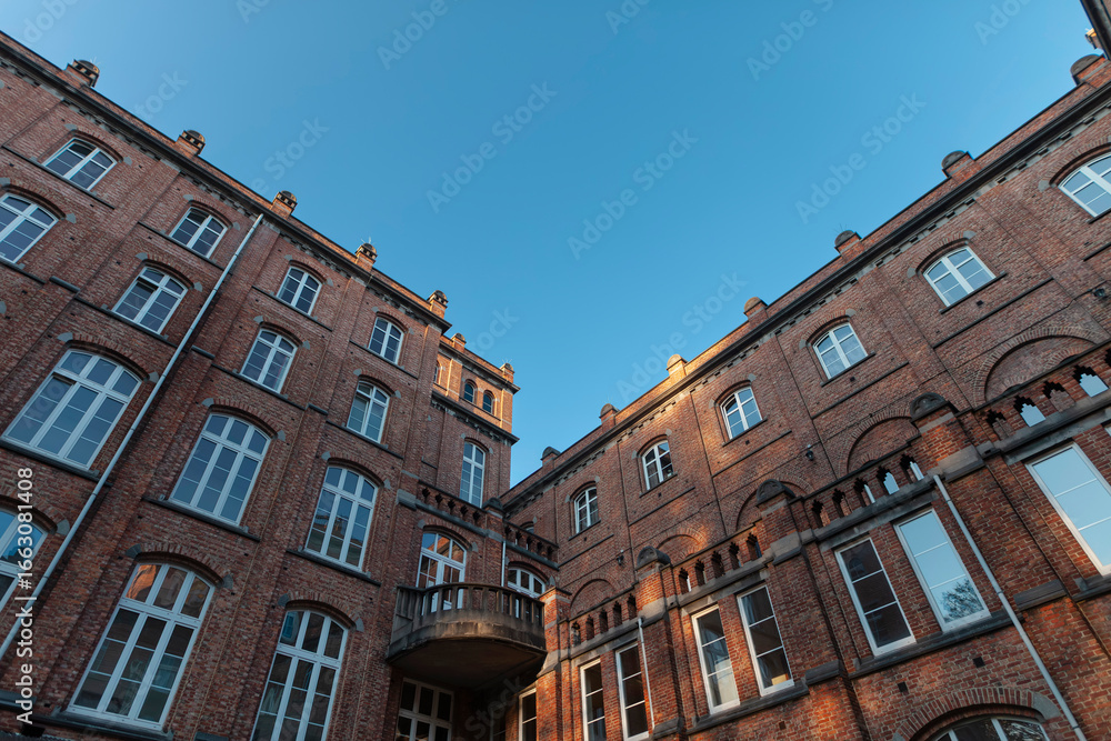 Fototapeta premium Dramatic upward perspective of historic brick courtyard showing multiple building levels and traditional architectural details