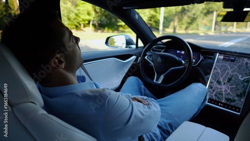 Male businessperson experience to ride an autonomous self driving electric car at urban road. Confident businessman resting during riding on electrical auto with autopilot at city. Slow motion