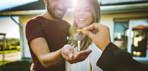 Photos Happy millennial couple receiving keys from realtor, purchasing real estate - Fa