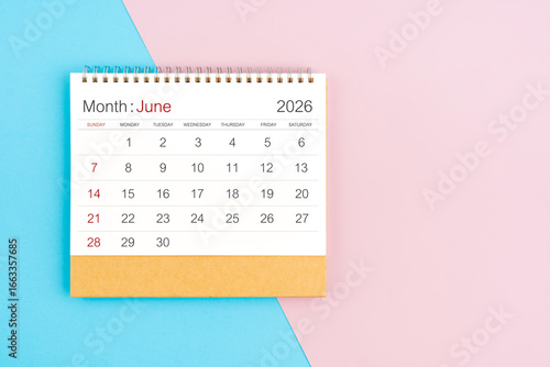 June 2026 desk calendar on blue and pink color background, with copy  space.