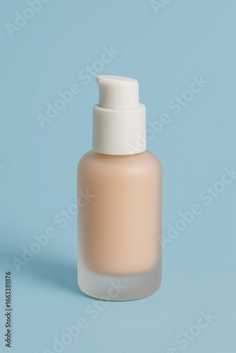 Close-up shot of a foundation bottle with a pump dispenser on a light blue background.