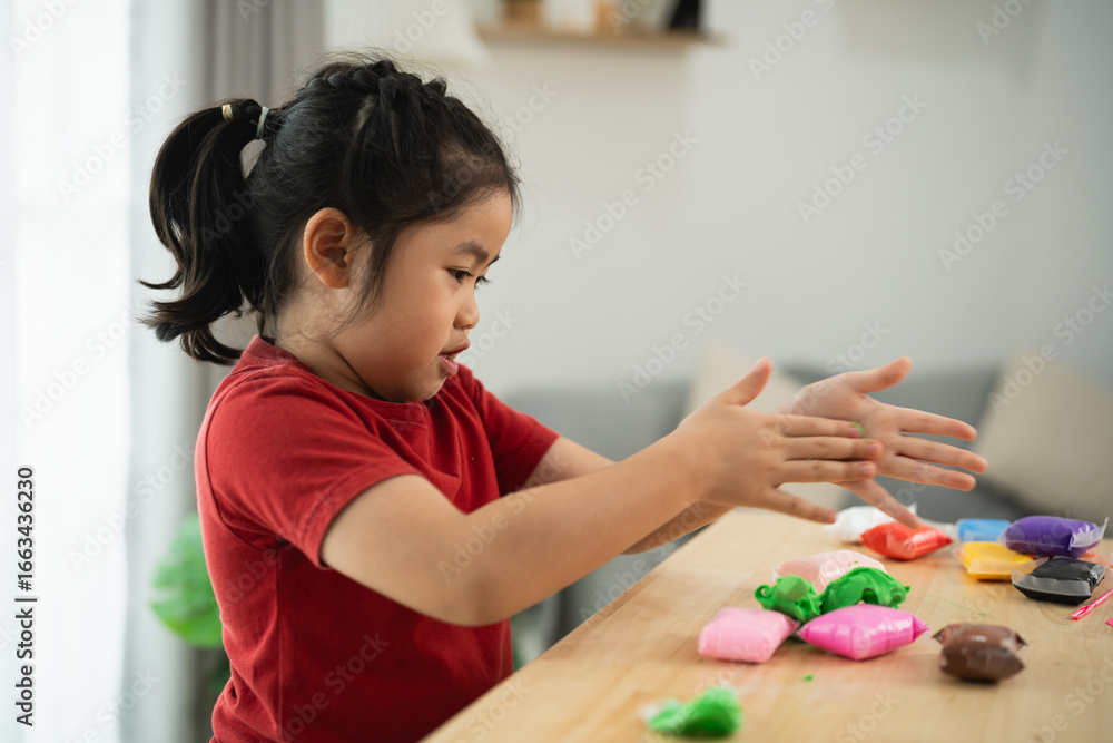 Young Girl Enjoys Creative Play with Colorful Modeling Clay on a Wooden Table in a Bright Indoor Environment Young Girl Enjoys Creative Play with Colorful Modeling Clay on a Wooden Table in a Bright Indoor Environment