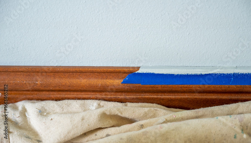 Φωτογραφία Interior painting project in a home with careful taping along the wooden trim in