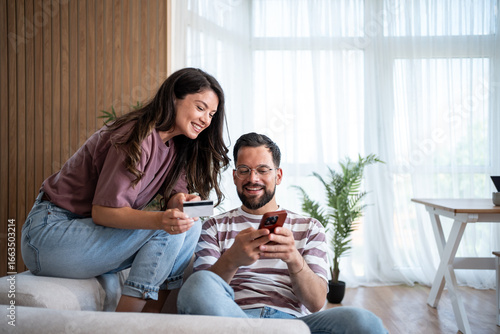 Happy couple making online payment using credit card and smartphone at home