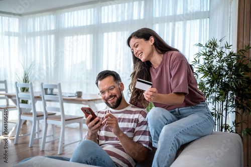 Couple using smartphone and credit card for online shopping at home