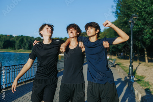 Konstfotografi Group of teenage boys laughing and walking together by the lakeside in summer