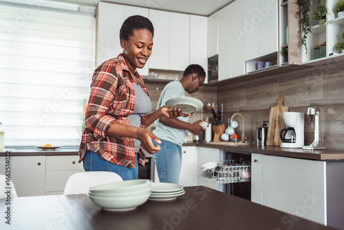 Obraz na plátně Couple Doing Dishes Together in Modern Kitchen