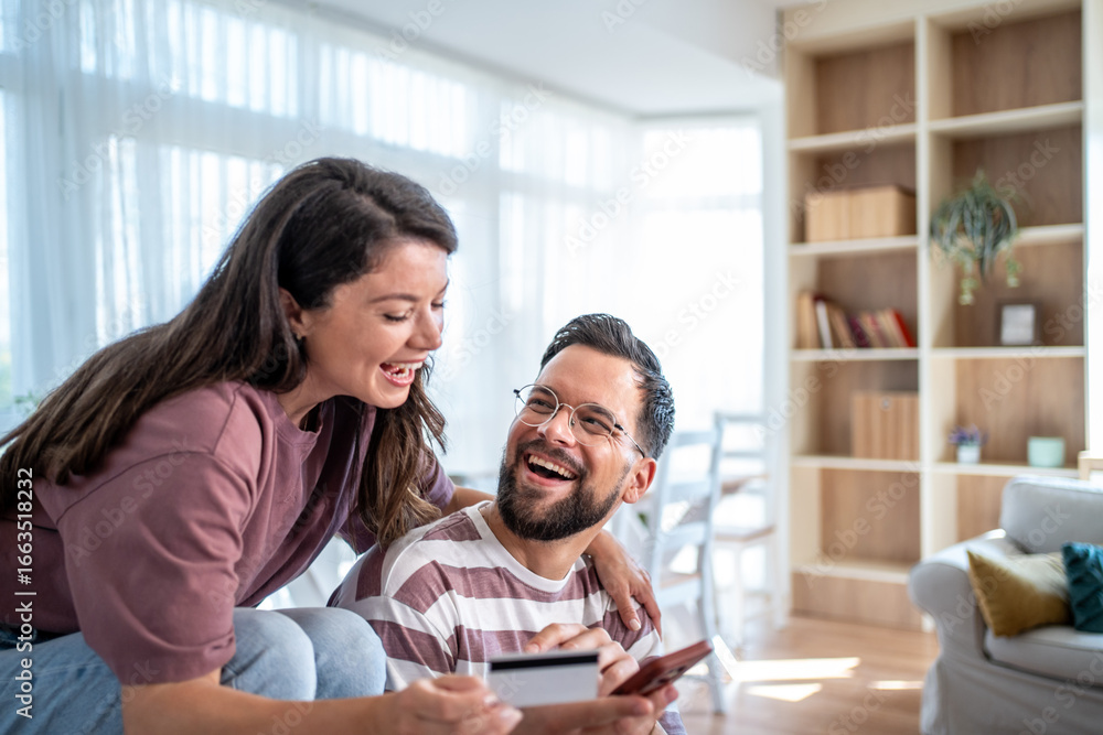 Obraz premium Happy couple making online payment with credit card at home