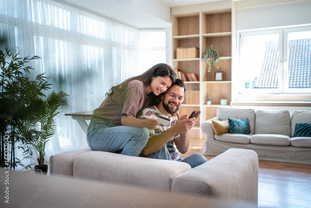 Obraz premium Happy couple making online payment using credit card and smartphone at home