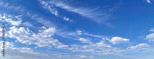 A vast expanse of a clear blue sky dotted with fluffy white clouds