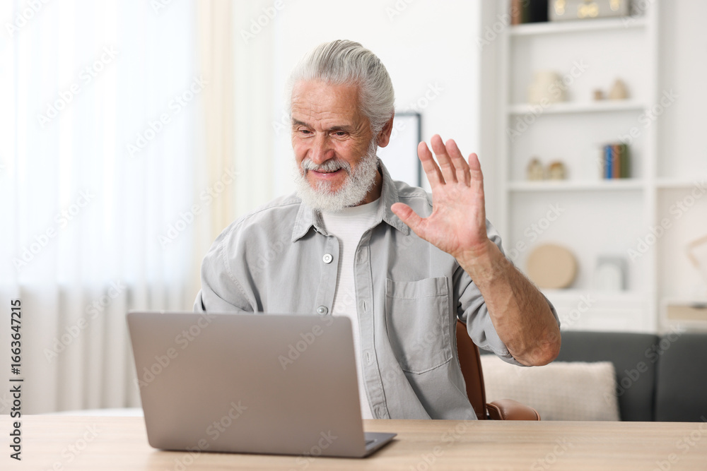 Senior man having online consultation with doctor via laptop at table indoors Senior man having online consultation with doctor via laptop at table indoors