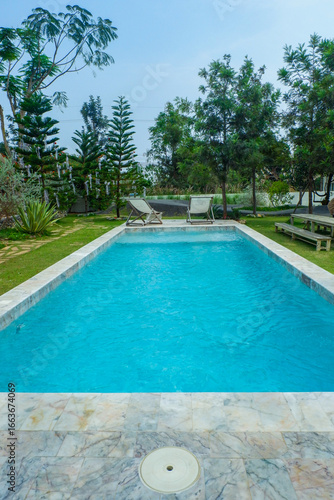 Empty swimming pool with sunbed and white umbrella in resort hotel for vacation leisure and white sand,resort neary sea and beach in summer.