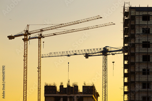 Construction of a new residential area using high-rise cranes at sunset.