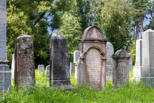 Canvas Print Old historical tombstones with Hebrew script in a grassy cemetery