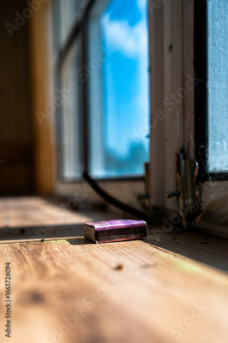 A matchbox by an unkempt window sill