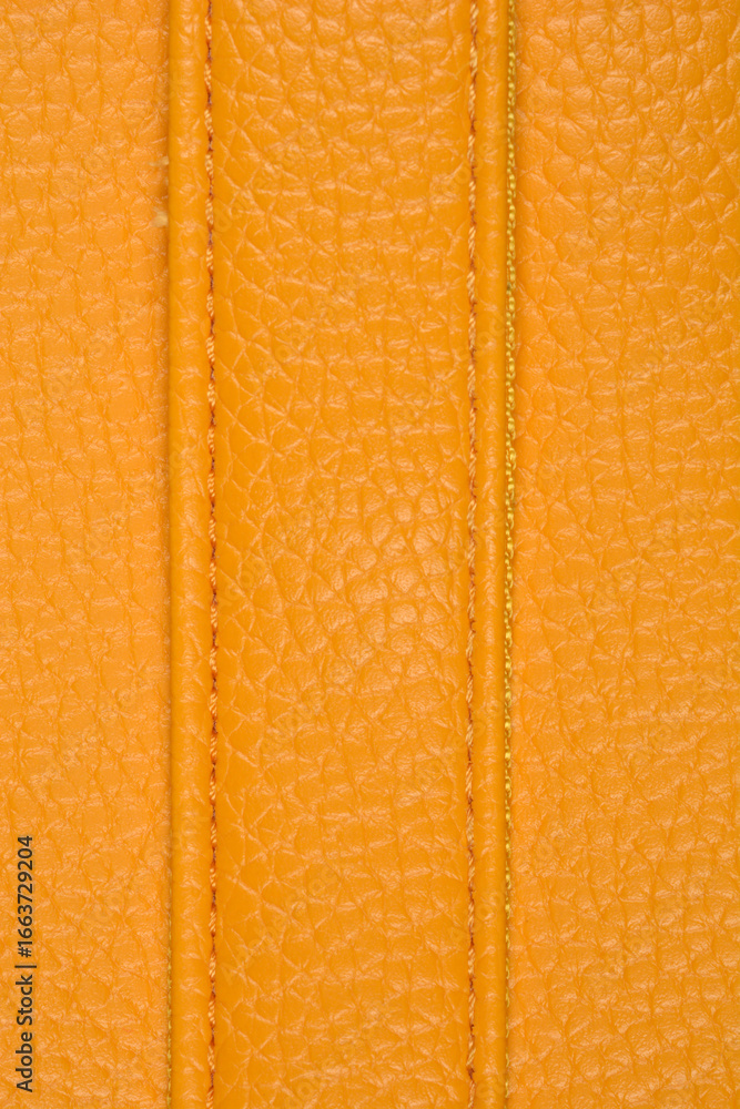 Fototapeta premium A close-up vertical shot of a textured yellow artificial leather surface, featuring two parallel lines of neat, matching-color stitching
