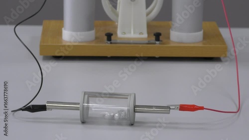 Physics demonstration of electrostatics experiment showing the transfer of electric charge between objects. Teacher explains principles of static electricity to students during a classroom lesson.