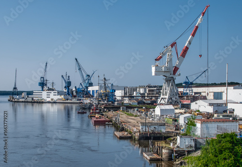 Industrial Docks in Maine:  Large cranes for loading and unloading cargo boats stand along the shoreline near Bath, Maine.
