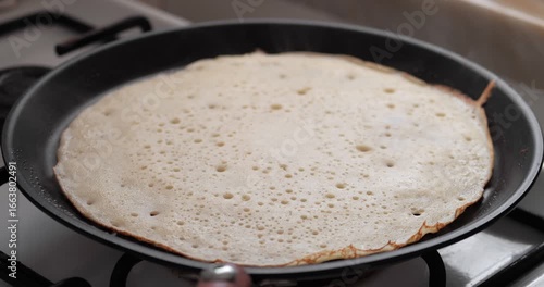 Wallpaper Mural A thin pancake cooking in a black frying pan on a gas stove. Bubbles form on the surface as it cooks evenly. Torontodigital.ca