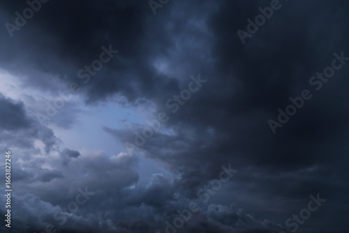 Epic Dramatic storm dark grey cumulus rain clouds against blue sky background texture, thunderstorm