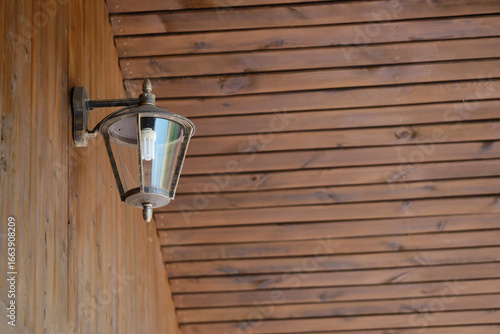Wooden wall and floor with old lantern holding modern bulb