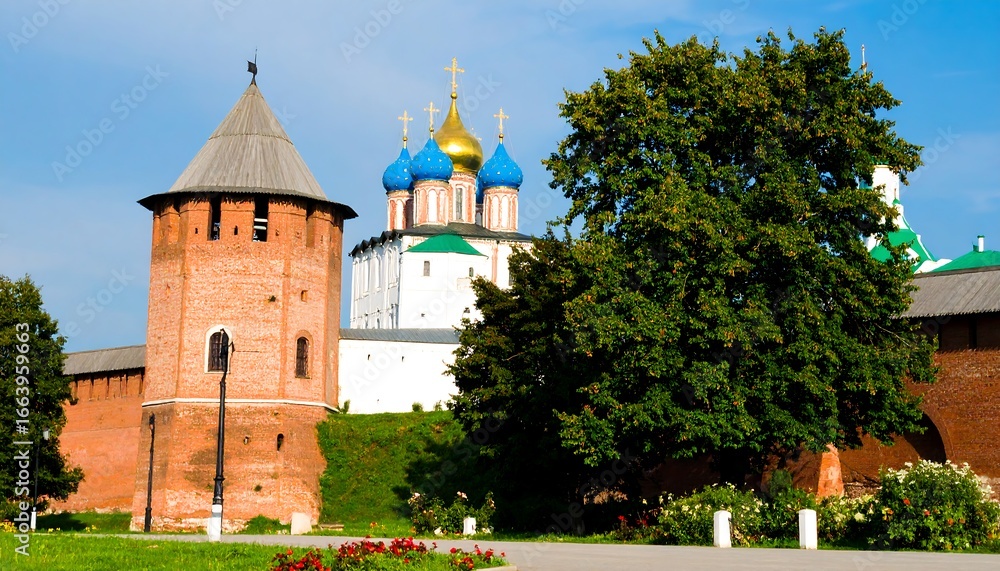 Obraz premium A picturesque scene of a historic red brick tower and a traditional Russian church, with lush green trees and a clear blue sky.