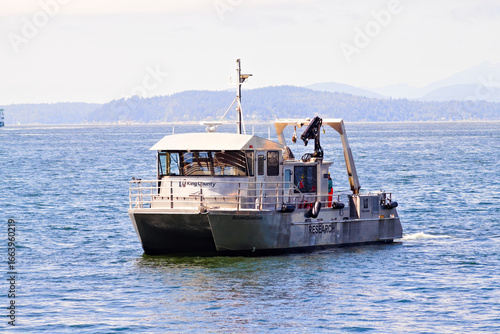 A sturdy research vessel glides across calm coastal waters, equipped with cranes and gear for scientific fieldwork, supporting marine studies, environmental monitoring, and data collection on the open