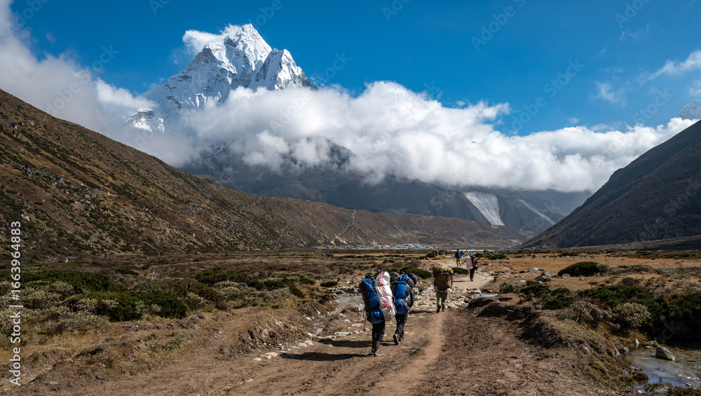 Fototapeta premium Porter carrying guest bags in Sagarmatha nationalpark in Nepal with beautiful view of Mt.Ama Dablam.