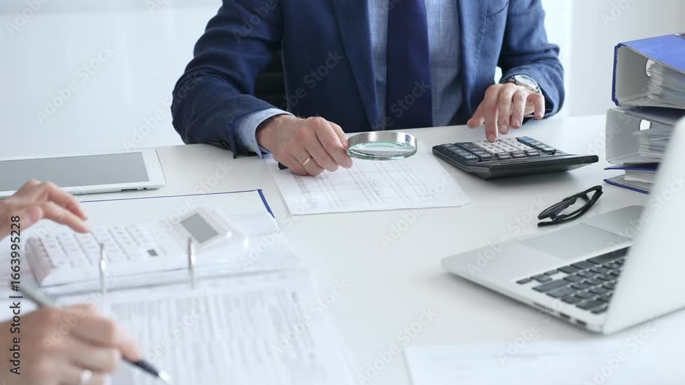 Business team analyzing financial documents, using calculators and laptop, working together on project in modern office. Audit and taxes in business Business team analyzing financial documents, using calculators and laptop, working together on project in modern office. Audit and taxes in business
