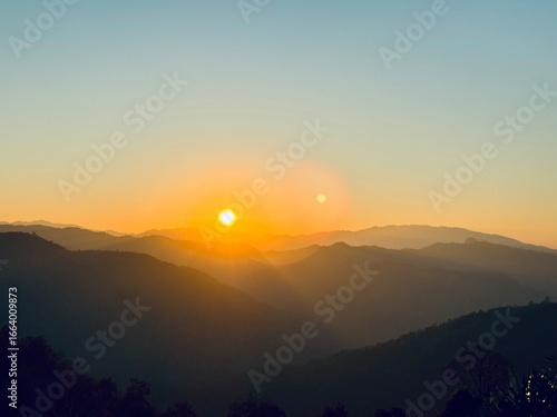 Wallpaper Mural A breathtaking view of a vibrant golden sunset over rolling mountain ranges, with a beautiful lens flare effect. Torontodigital.ca