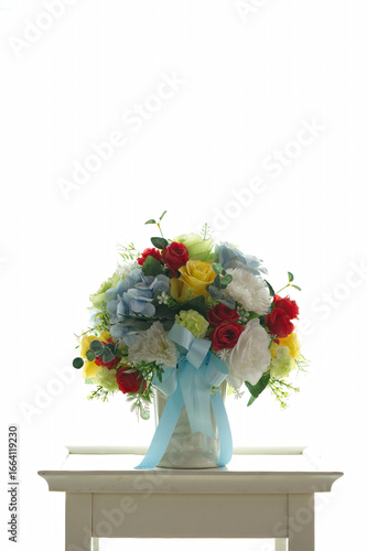 The colorful fake flower vase is located on a white table