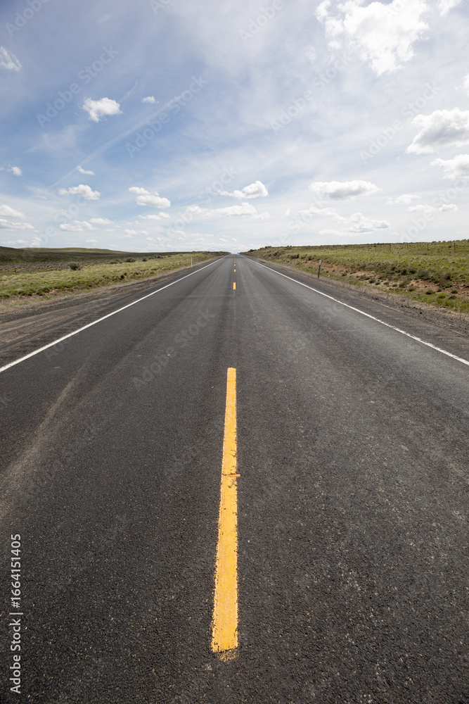 Naklejka premium A long, empty road with a yellow line down the middle