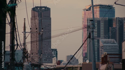 Dramatic Tokyo Sunset Facing Shibuya with Network of Urban Cables and Lights – Narrow street framed by silhouetted wires leads to high-rise apartments glowing in dusk.
