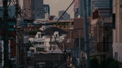 Peaceful Tokyo Evening Street Facing Shibuya with Silhouetted Power Network – Apartment building and power lines stand dark against glowing horizon with sunset colors above.