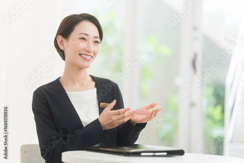 Cuadro en lienzo ジャケット着た笑顔の日本人女性が話をしている。