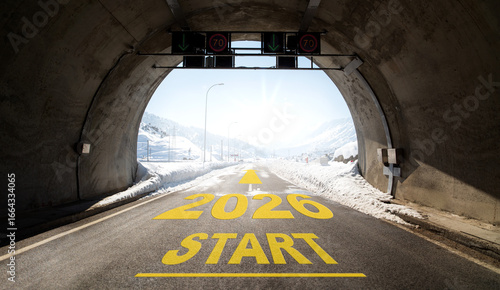 The words ‘2026 START’ written on a road emerging from a tunnel between snow-covered mountains. An inspiring concept symbolising the start of the new year, hope, goals and looking ahead.