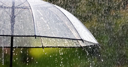 Raindrops falling on transparent umbrella close-up. Slow motion