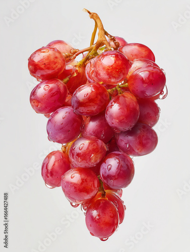 Close up of a bunch of red grapes with water droplets on a white background