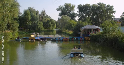 Kyiv, Ukraine , 22.08.2023 Lake in a beautiful city park on a sunny day. People  renting boats and catamarans and relax going for a row. Active leisure with children