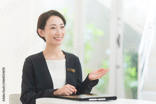 ジャケット着た笑顔の日本人女性が話をしている。