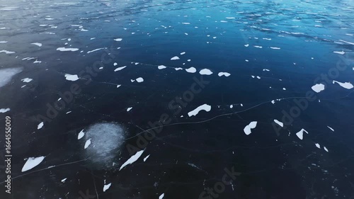 Thick ice on the water. Fishermen walk on a frozen lake. Winter landscape with patterns on ice