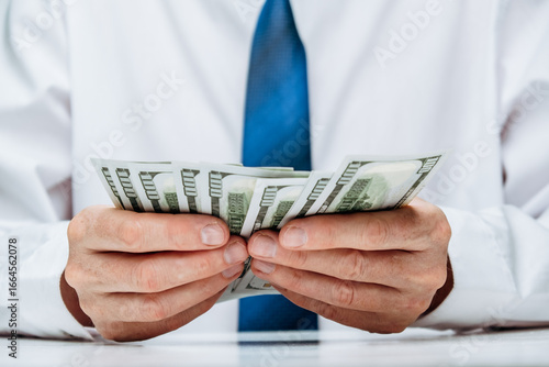 well-dressed person carefully counts stack cash while sitting at desk in professional office. concept investment, success, financial prospects and career growth. focus is on money in hand. close up.