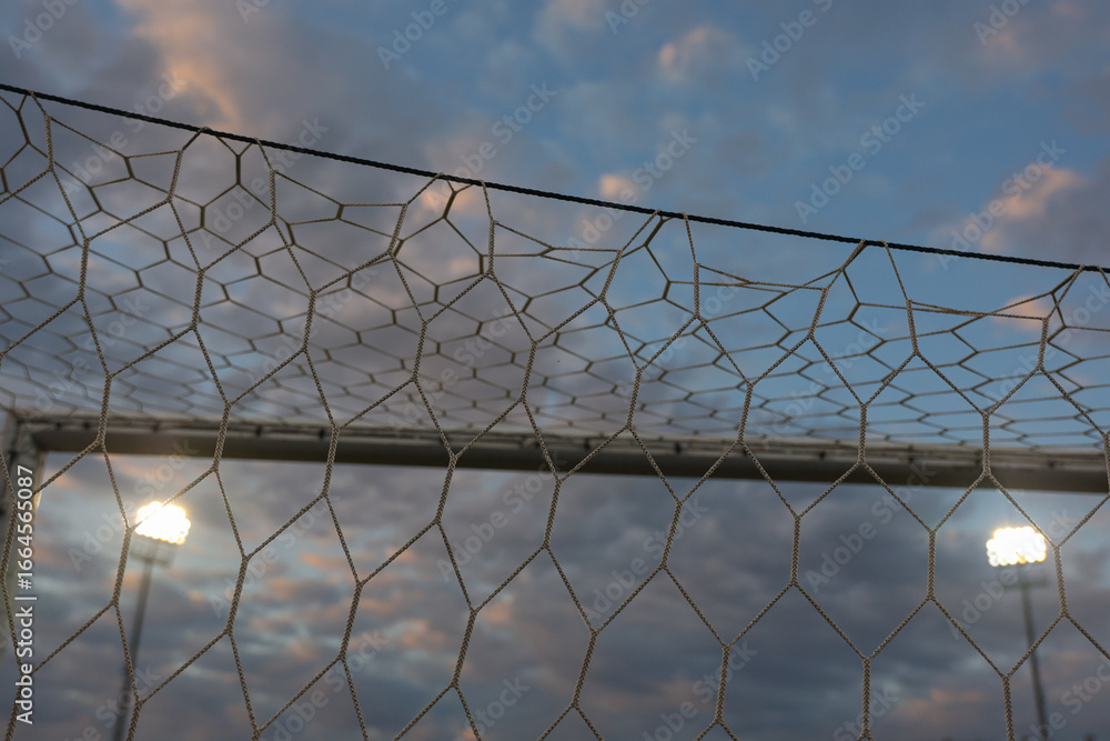 Football Stadium Floodlights at Night Seen Through Goal Net – Concept of Soccer and Sport Atmosphere Football Stadium Floodlights at Night Seen Through Goal Net – Concept of Soccer and Sport Atmosphere