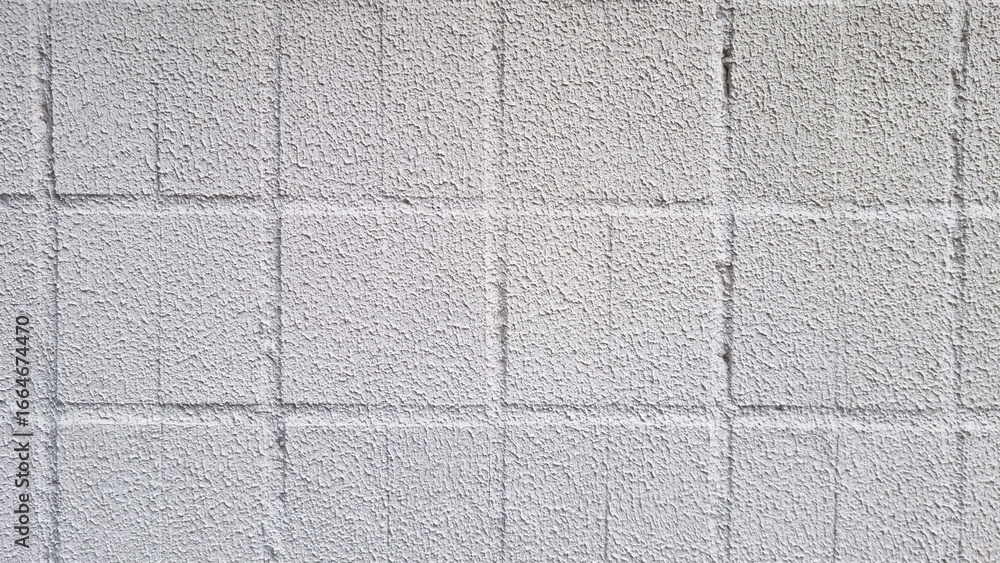 Fototapeta premium Concrete wall surface with square tile pattern and rough textured white plaster coating. Clean architectural background photography