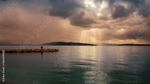Calm seascape with dramatic golden sky and sun rays breaking through clouds, symbolizing peace, hope, and reflection in nature.