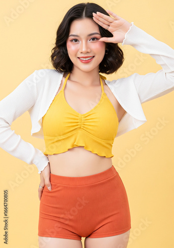 Happy Asian girl in yellow bikini looking into the distance, summer travel concept.