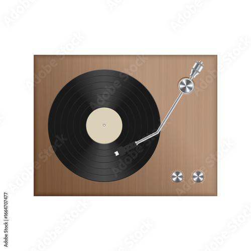 A record player spins a black vinyl on a wooden surface. It has a metal arm with a needle and two silver knobs at the bottom right corner. The record is black with a light label.