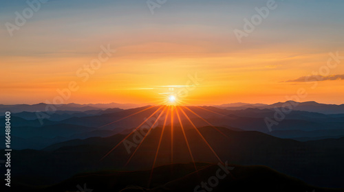 The sun is setting over a mountain range, casting a warm glow over the landscape