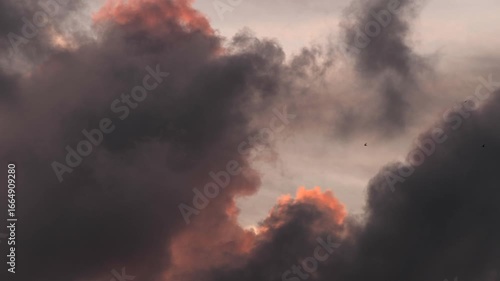 Dramatic clouds fill the sky with shades of gray and hints of orange. The scene captures a moody atmosphere, suggesting an impending storm or sunset.