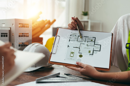 Architect presenting a detailed house plan to a client during a professional meeting, fostering collaboration and discussing design elements